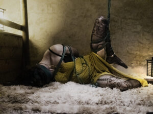Une esclave est attaché dans une magnifique robe jaune par des cordes de shibari vert.
